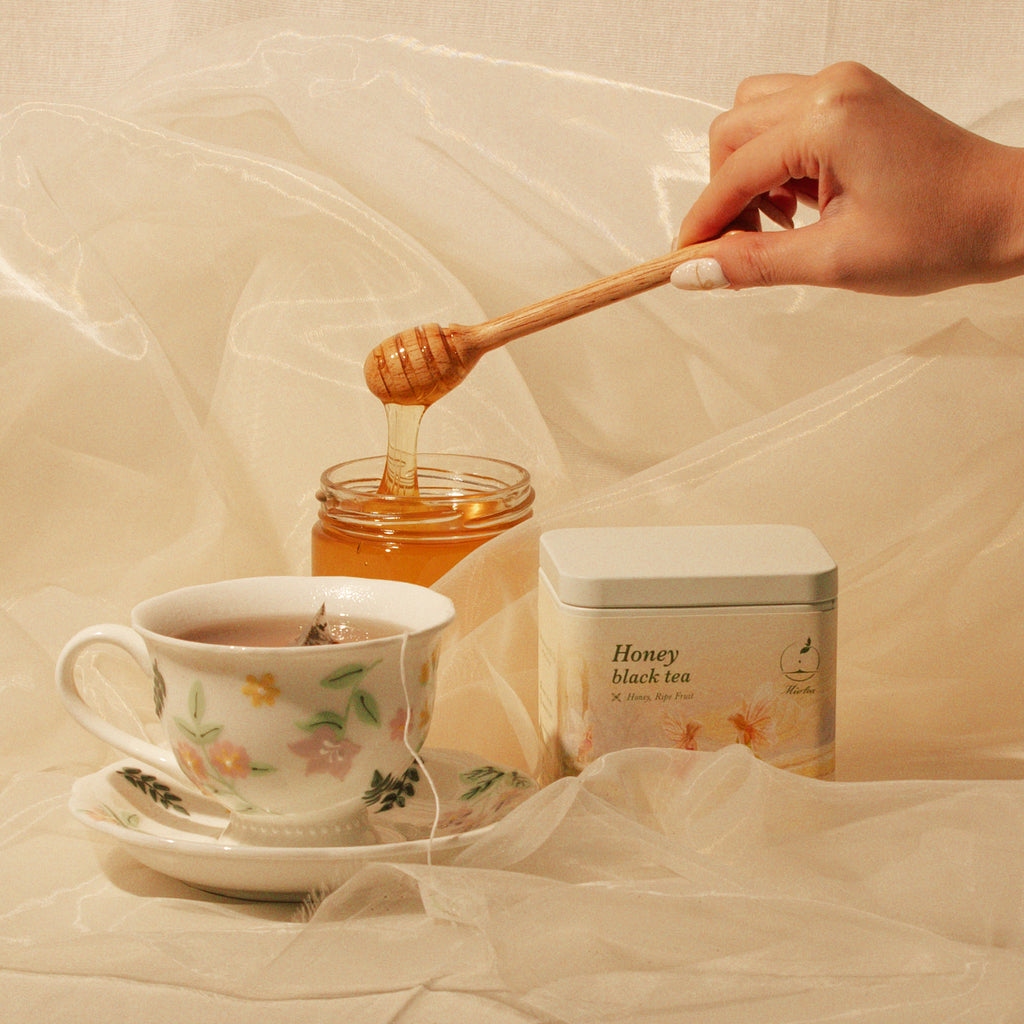 Honey Black Tea tin beside brewed tea and a jar of honey.