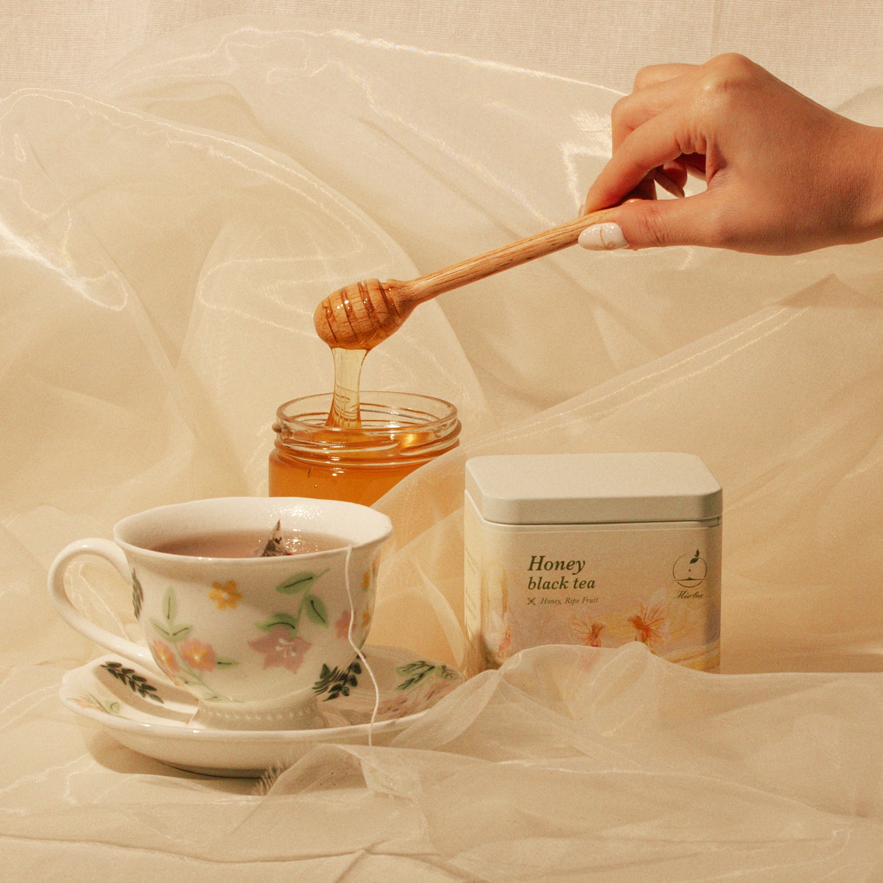 Honey Black Tea tin beside brewed tea and a jar of honey.