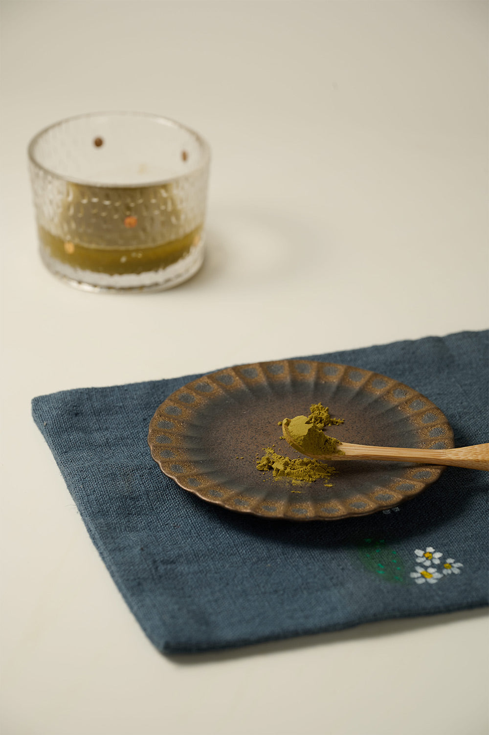 Milk Oolong Tea Powder on a spoon beside a ceramic plate.