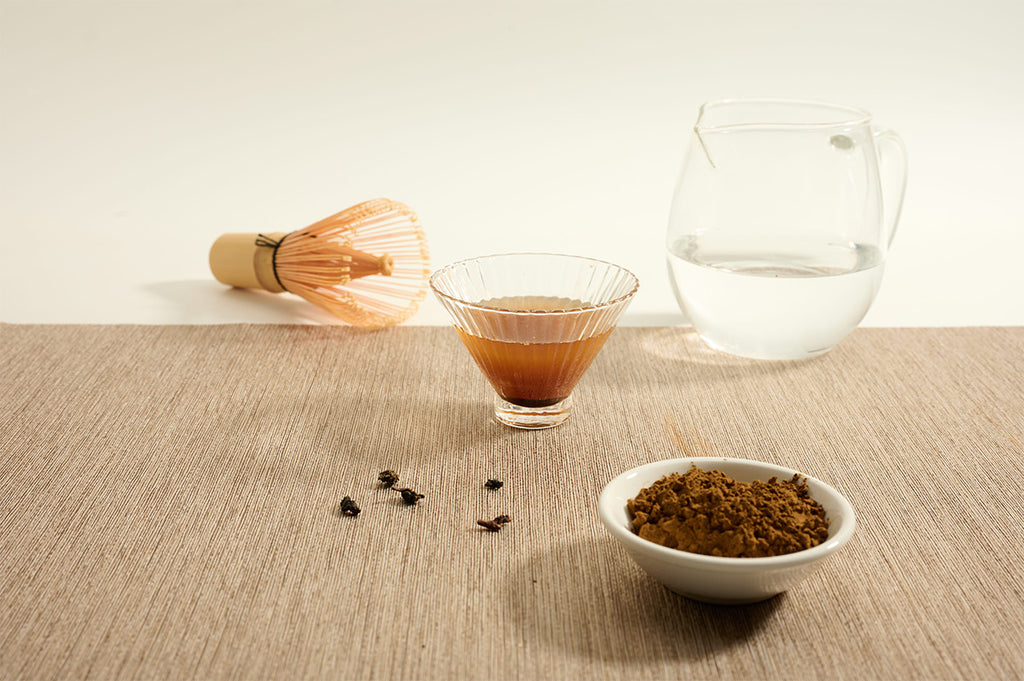 Ruby Black Tea Powder beside brewed tea and bamboo whisk. 
